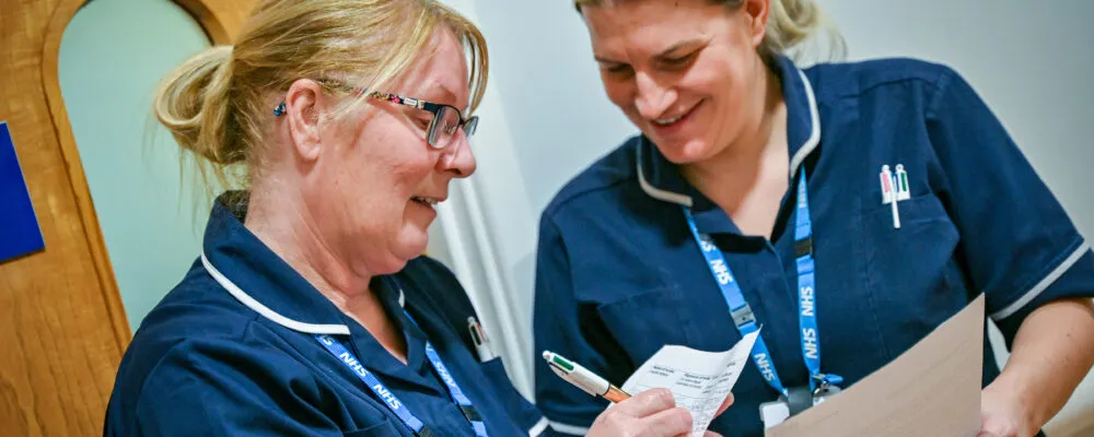 Two female nurses looking at paper