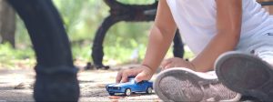 A photograph of a toddler playing with a toy car