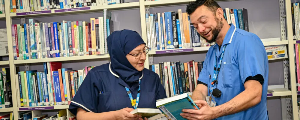 Two members of staff looking at a book