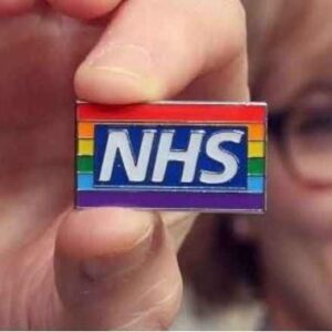 Person holding NHS rainbow badge