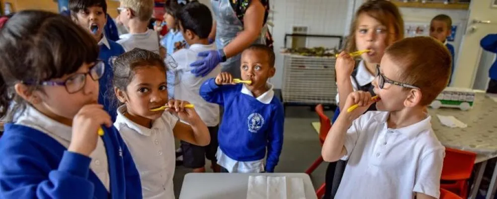 A photograph of children at school being supervised whilst brushing their teeth