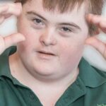 Photograph of a child with Downs using Makaton signing