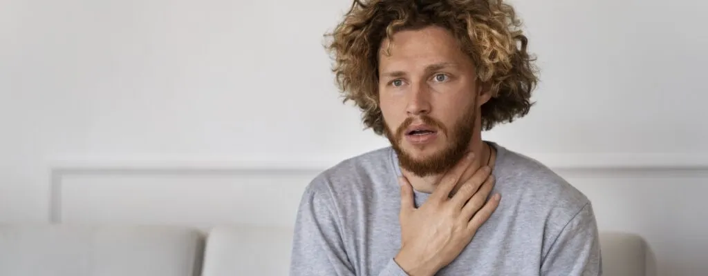 Photograph of a man touching his throat